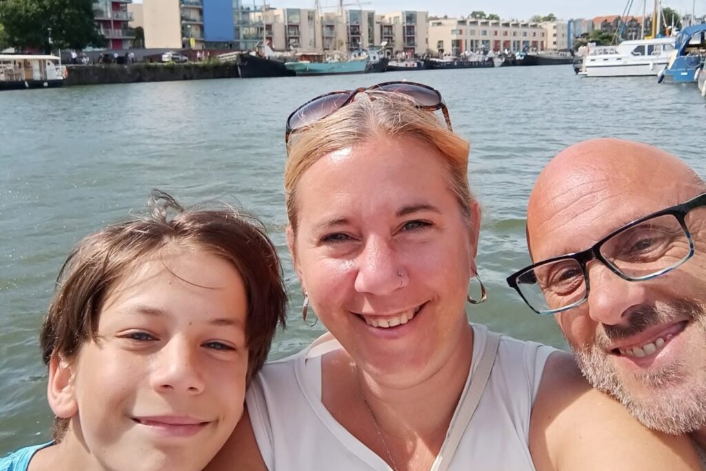 A family of three smiling together during their house-sitting journey