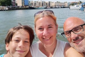 A family of three smiling together during their house-sitting journey